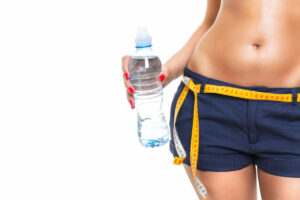 a woman holding a water bottle with measuring tape on her waist