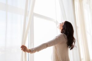 woman opening the window curtains